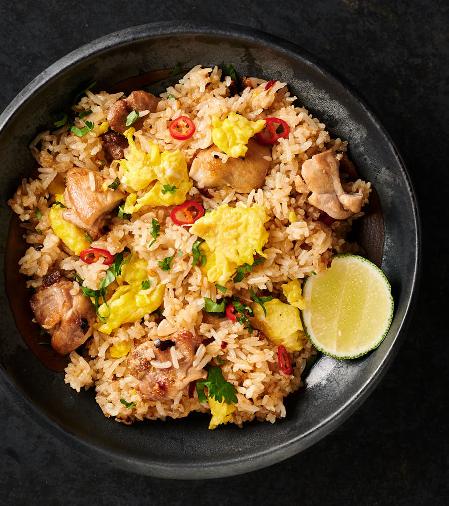 Thai fried rice in a dark pottery bowl from above.