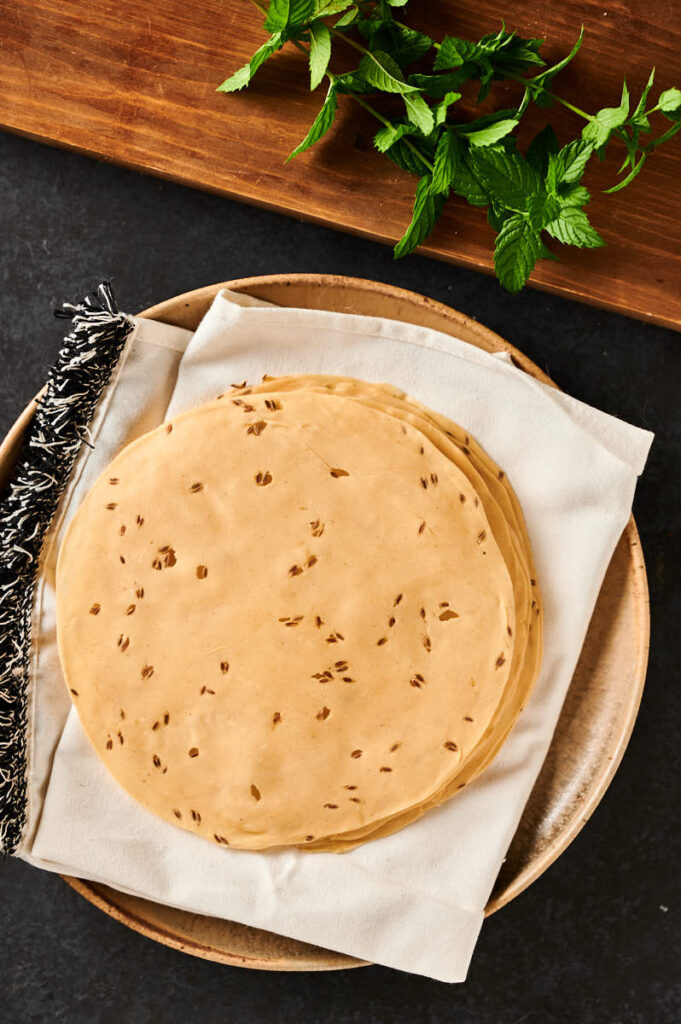 Uncooked store bought papadum on a plate from above.