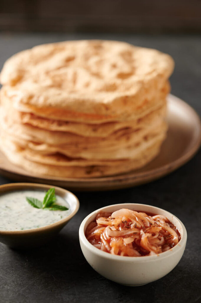 Red onion chutney in front of stack of papadum