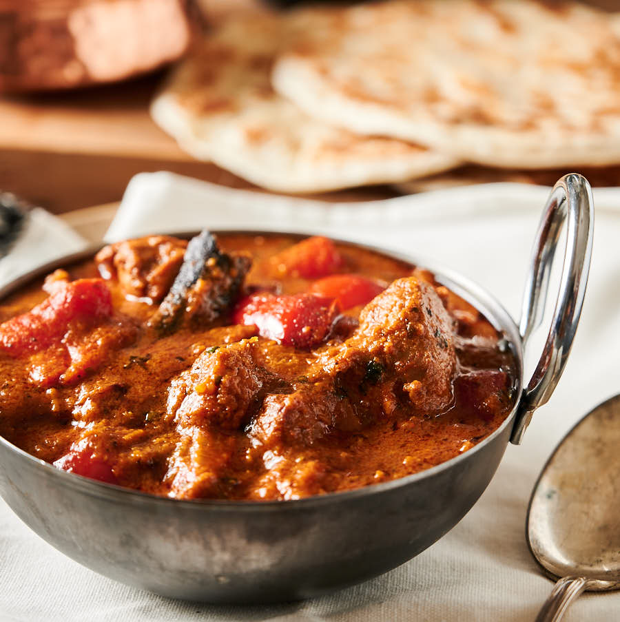 Lamb rogan josh in a black steel bowl from the front.