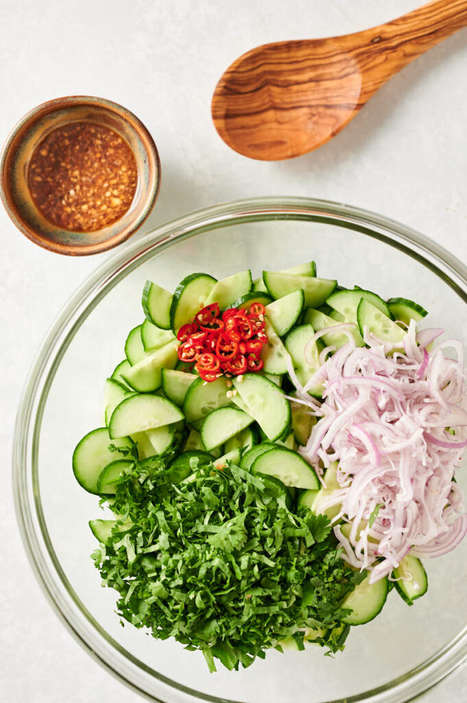 Cucumber, Thai chilies, cilantro and shallots in a bowl from above.