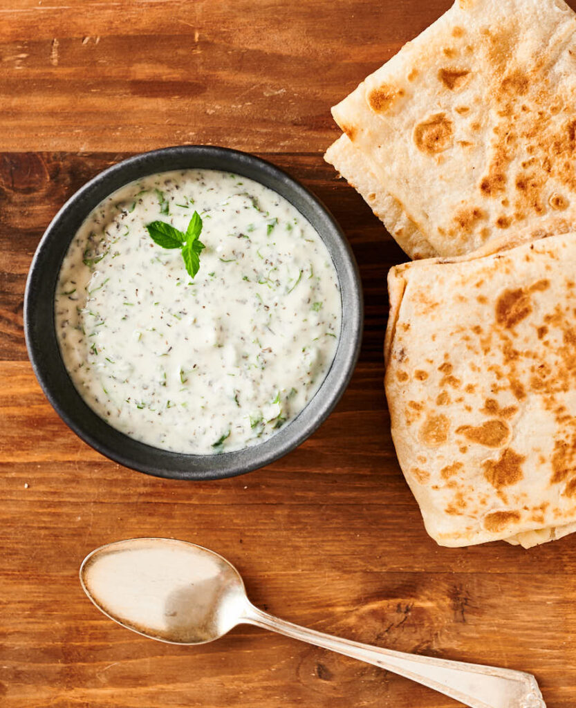 Mint raita and mutton roti on a cutting board from above.