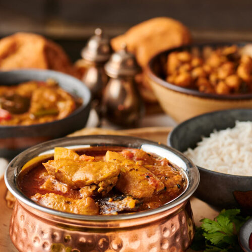 Murgir jhol table scene with rice and chickpeas from the front.