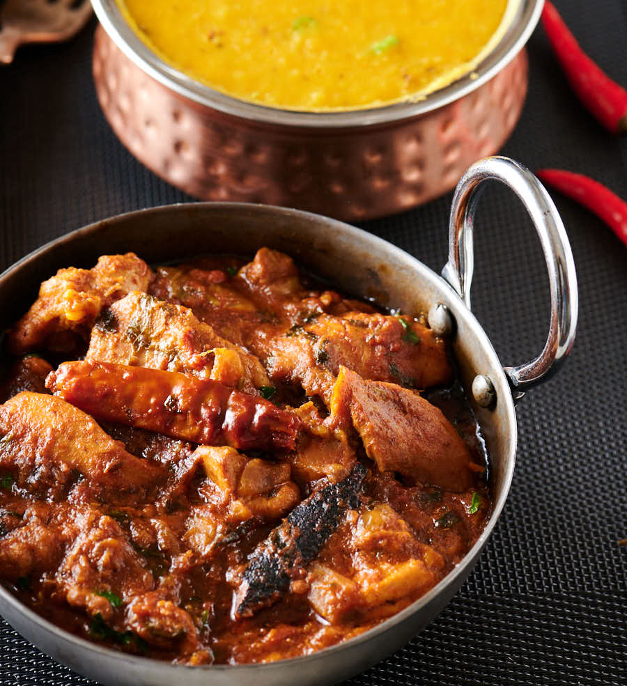 Indian style serving dish full of chicken bhuna from the front.