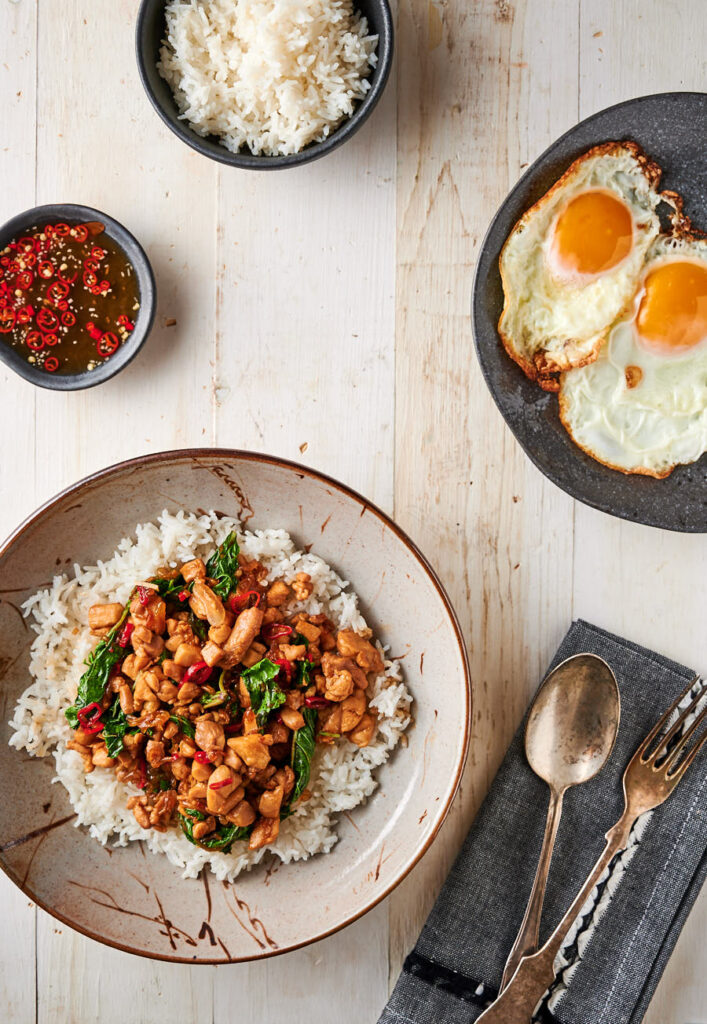 Thai basil chicken table scene - with rice, fried egg and nam prik plate