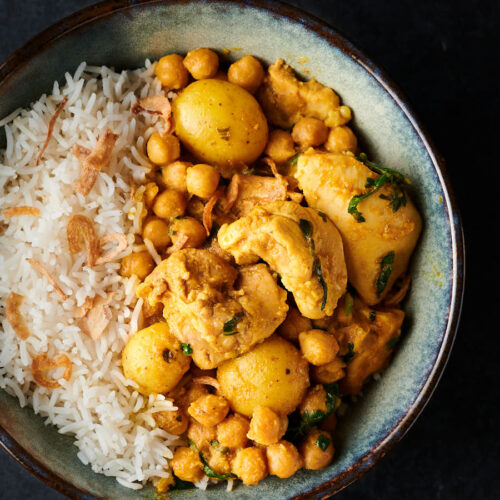Bowl of chickpea and chicken curry with rice from above.