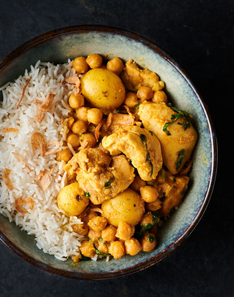 Bowl of chickpea and chicken curry with rice from above.