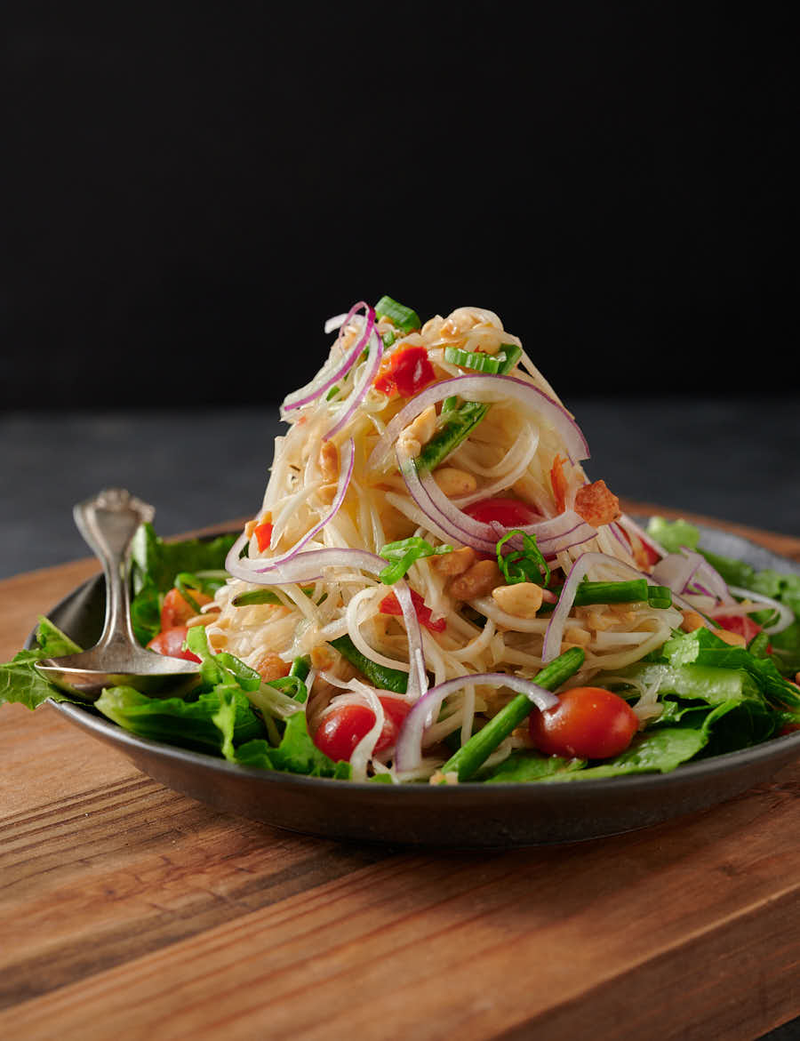 Mountain of som tam - papaya salad on a bed of greens from the front.