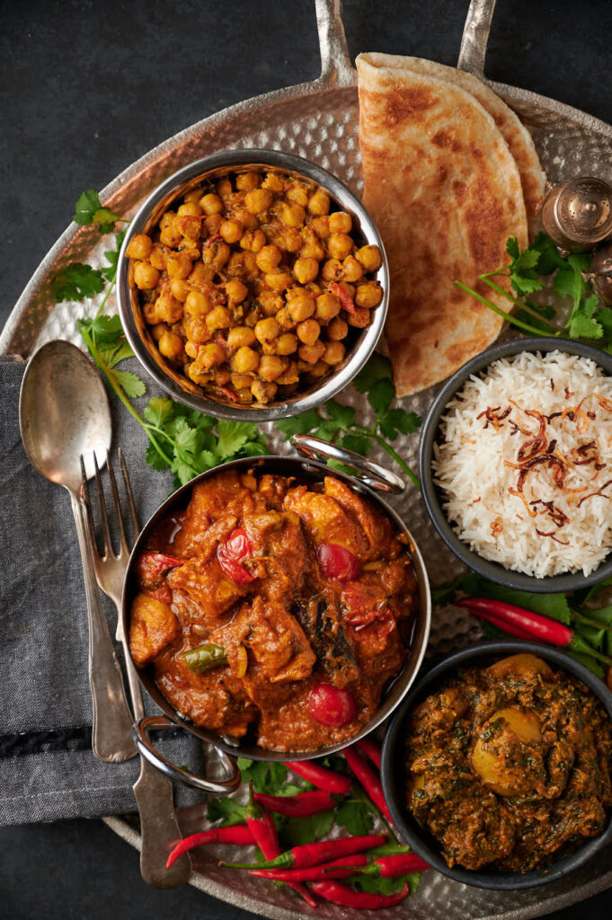 Garlic chilli chicken table scene with parathas, rice, chana and saag aloo from above.