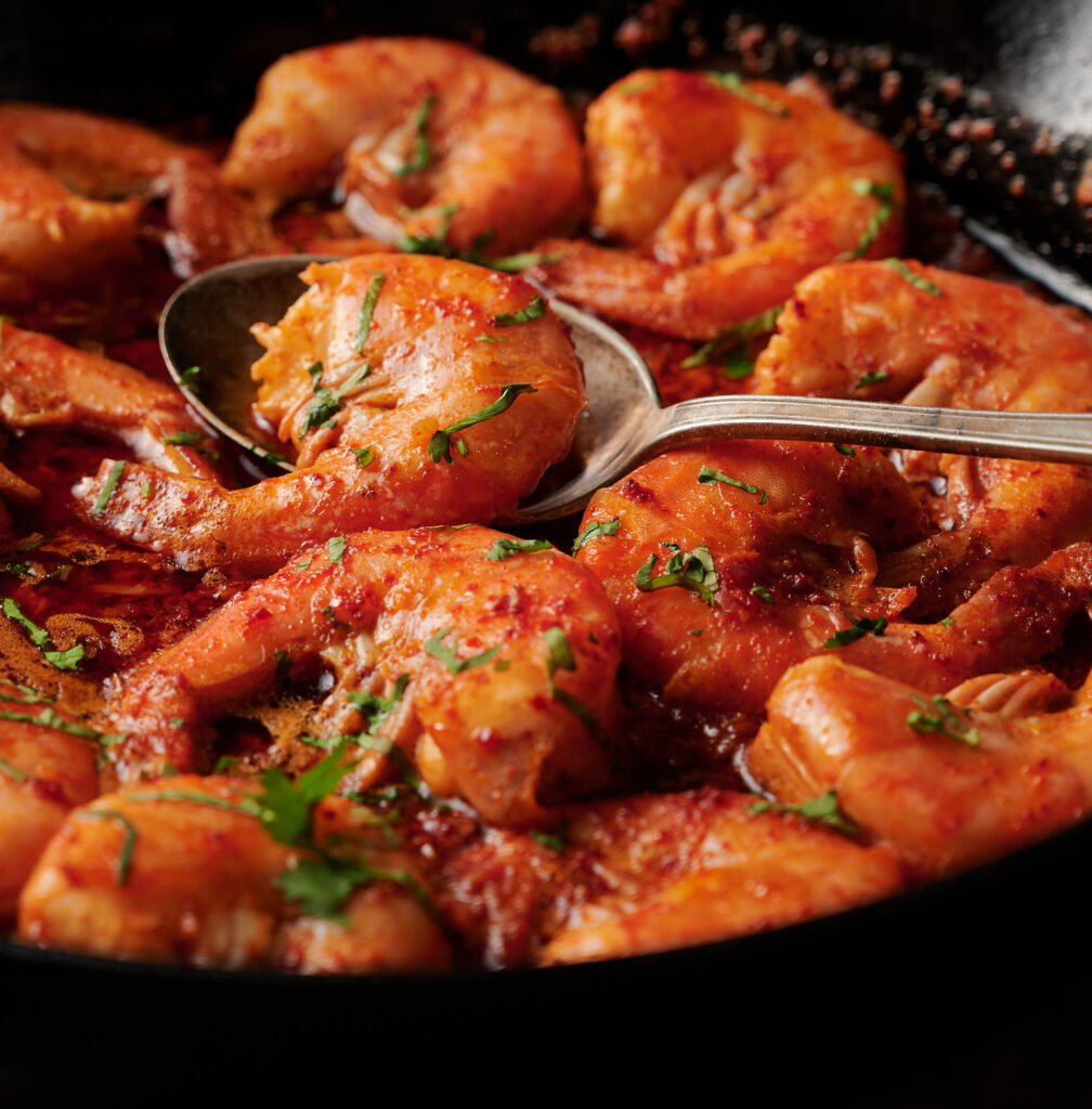 Close-up of korean bbq shrimp in a pan with a spoon.