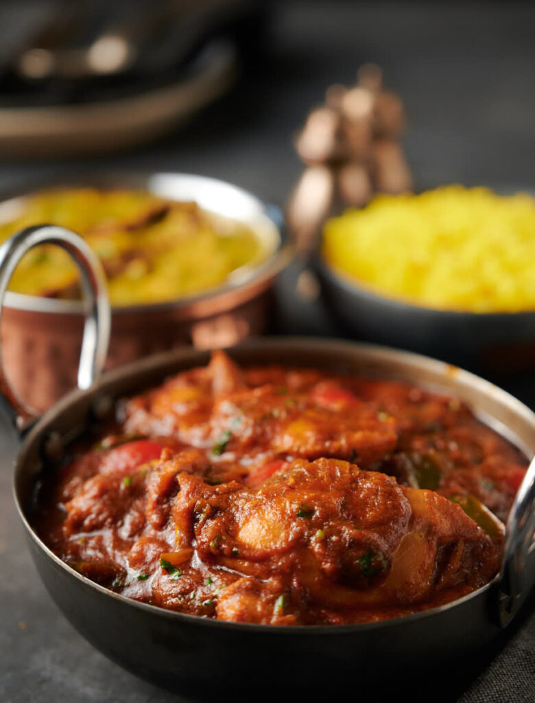 Indian green chili chicken curry with rice and dal palak from the front.