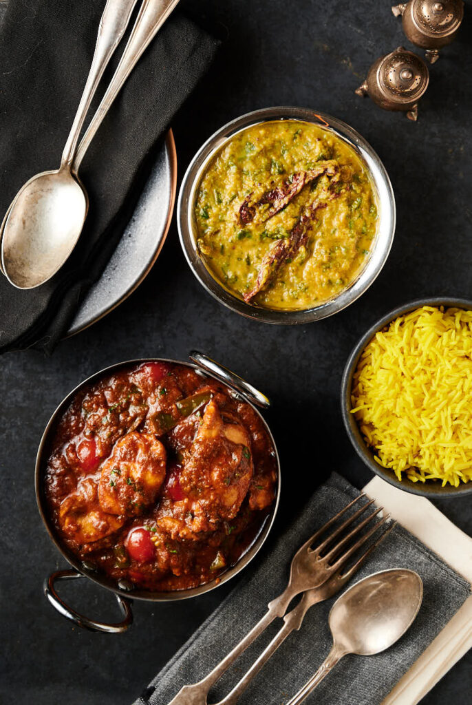 Indian hotel style green chili chicken curry, pilau and dal palak table scene from above.