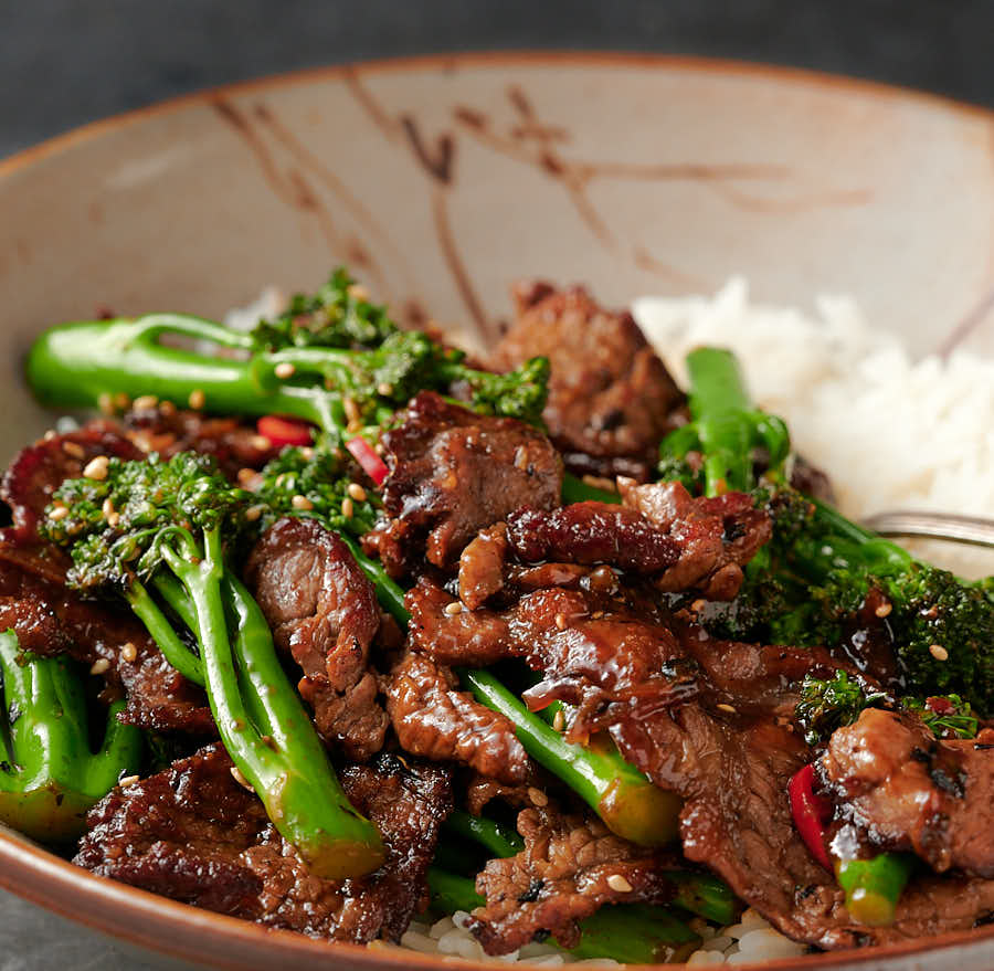 Close-up of Thai beef and broccoli in a bowl with rice from the front.