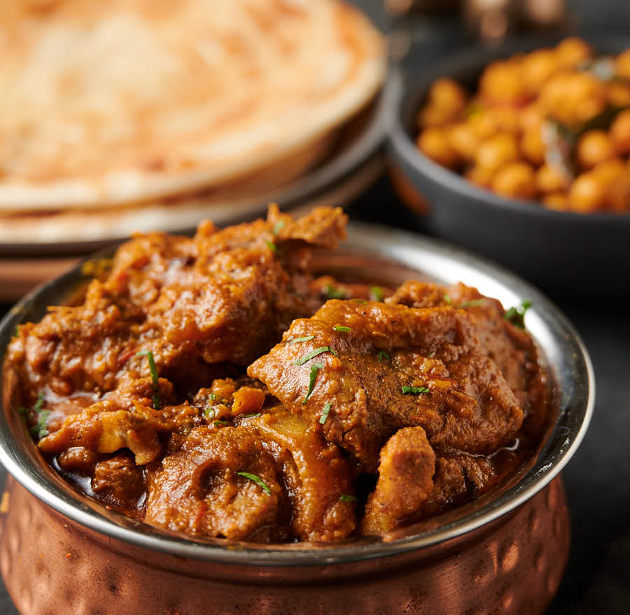 Close-up of lamb madras in a hammered copper bowl.