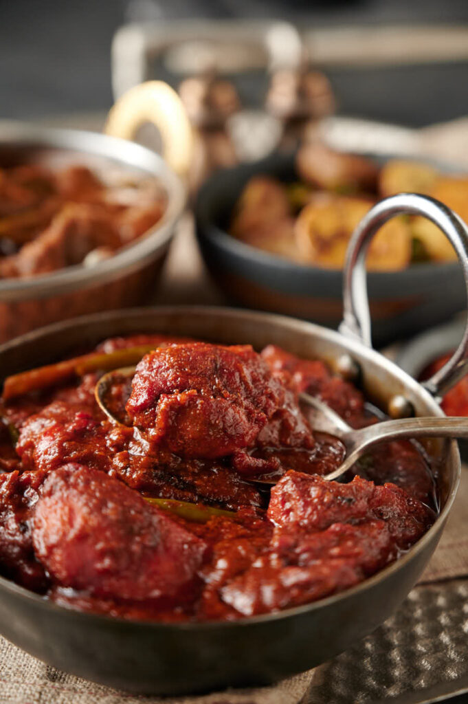 Close-up of a spoonful of naga chicken tikka curry from the front.