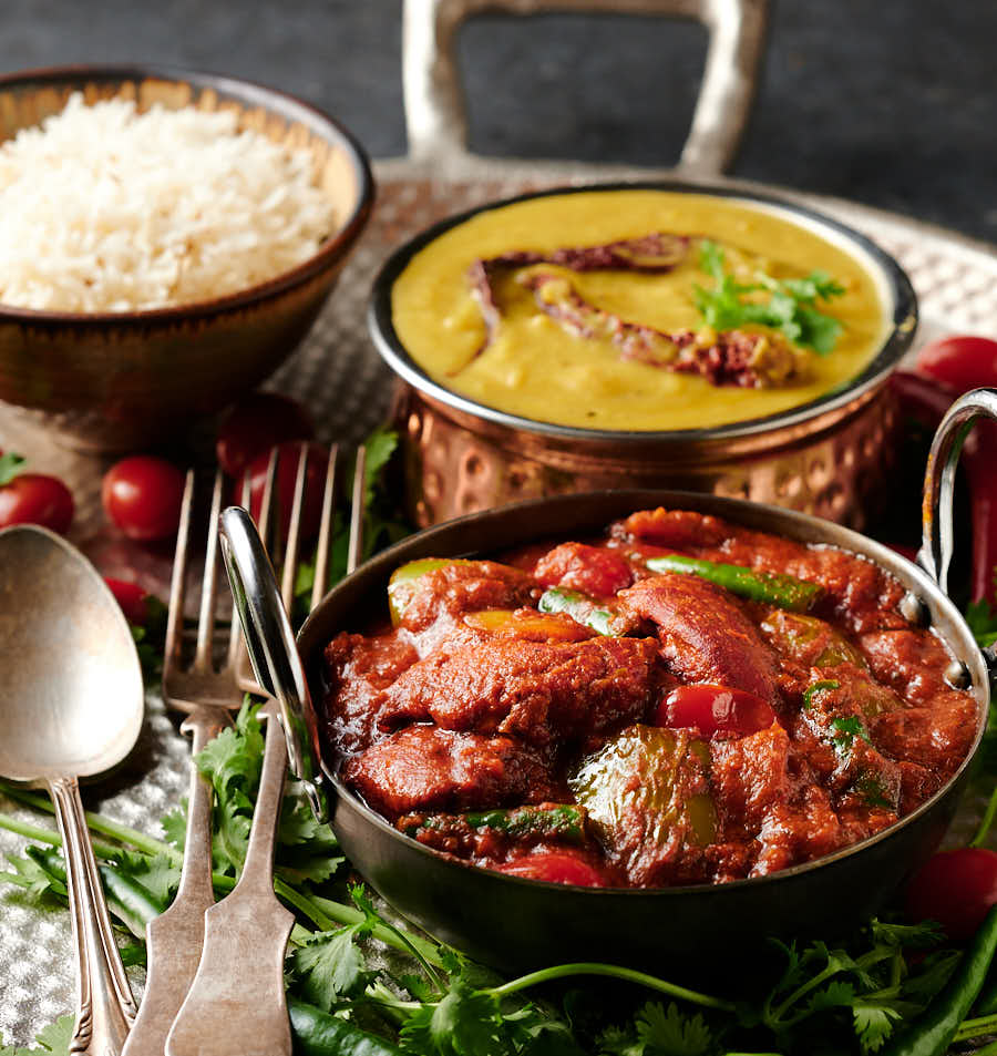 Table scene of chicken tikka jalfrezi, dal and rice.