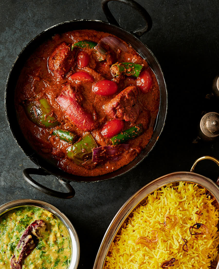 Table scene chicken tikka jalfrezi, rice and dal palak from above.