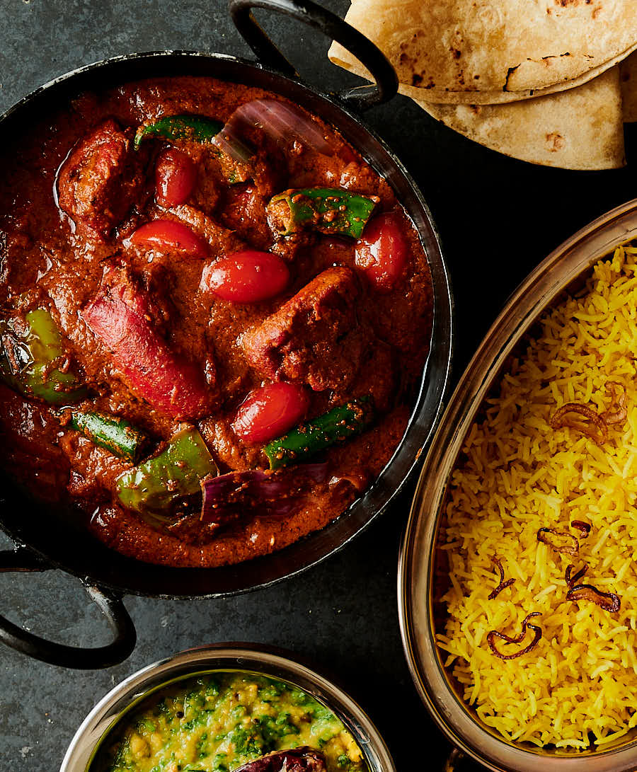 Chicken tikka jalfrezi in a kadai with rice and dal palak from above.