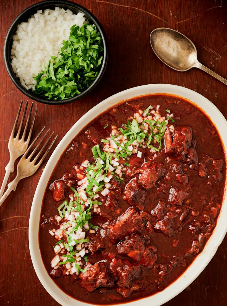 Birria de res table scene with garnishes and cutlery from above.