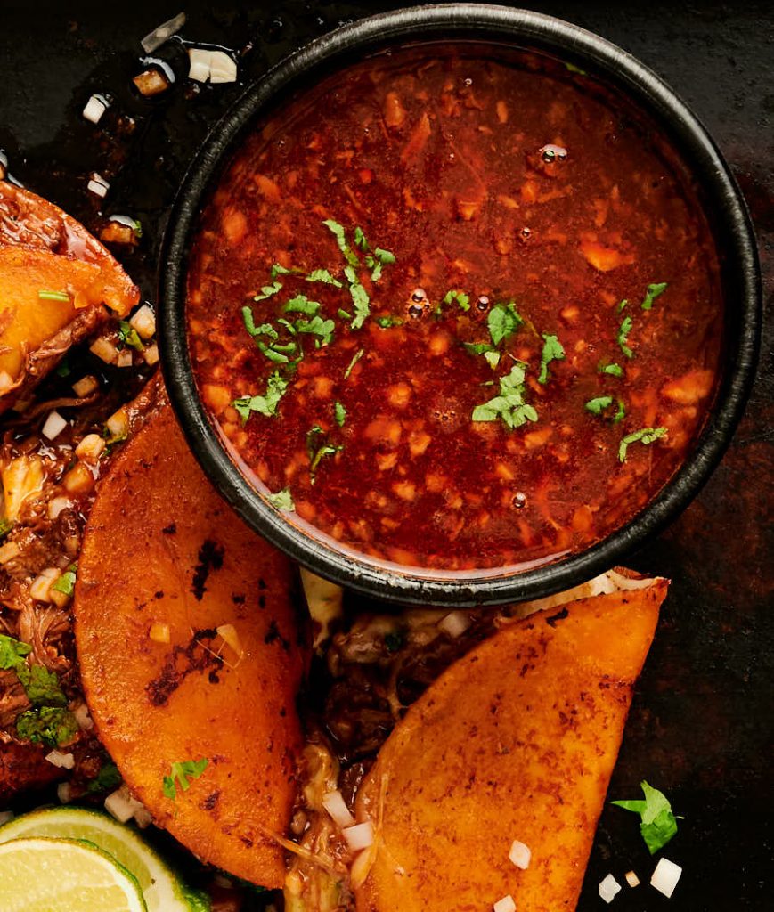 Bowl of birria de res consomé from above.