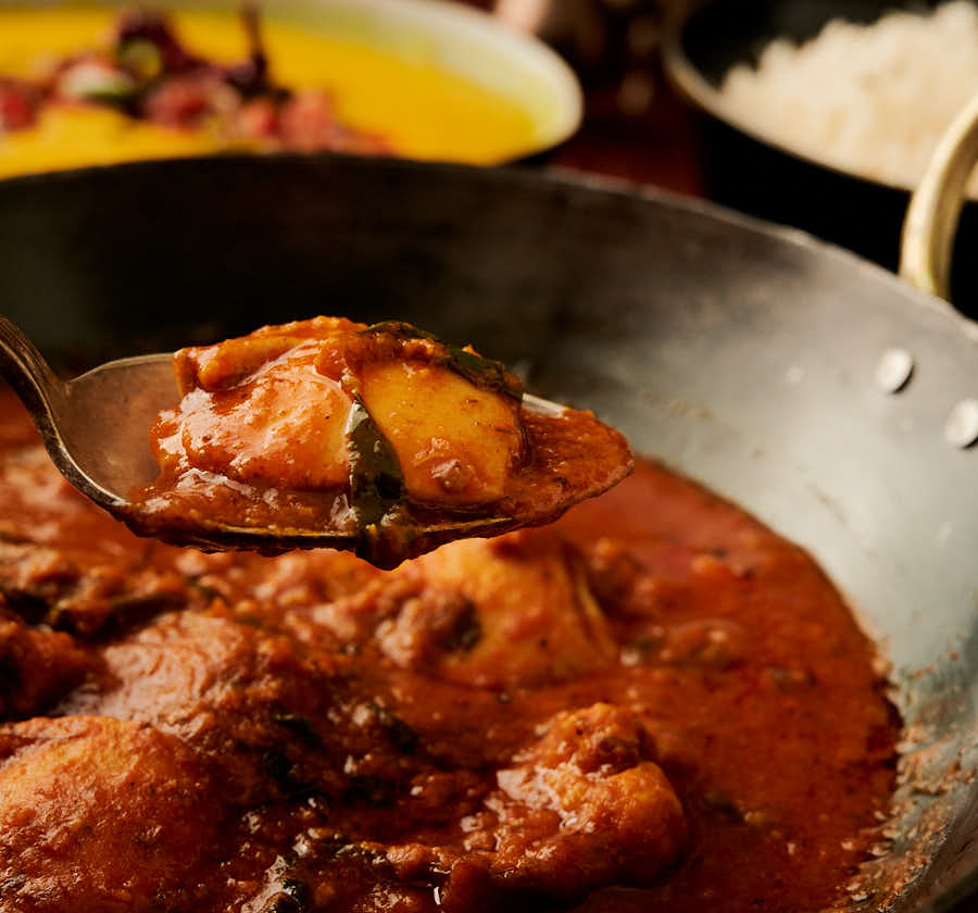 Spoon full of methi chicken from the front.