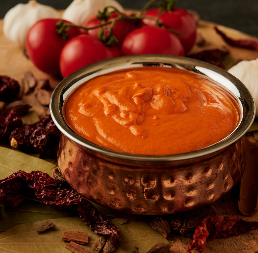 Bowl of makhani gravy in a hammered copper bowl from the front.