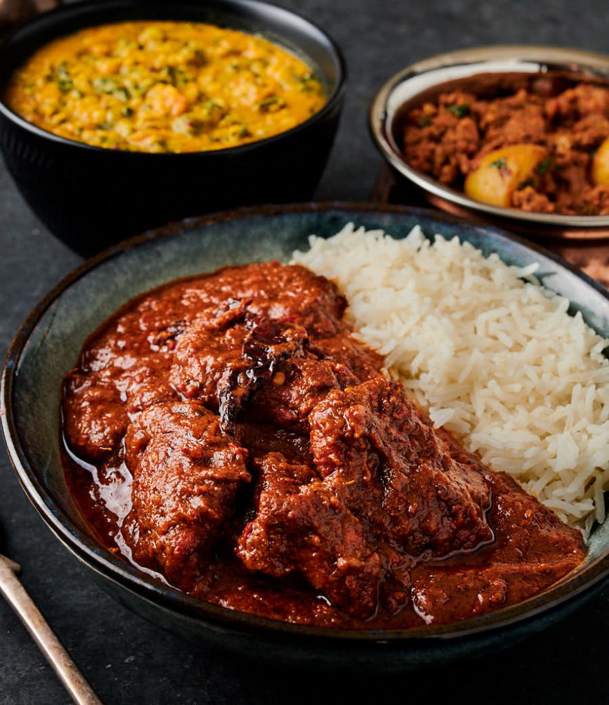 Bowl of chicken vindaloo with rice in a bowl from the front.