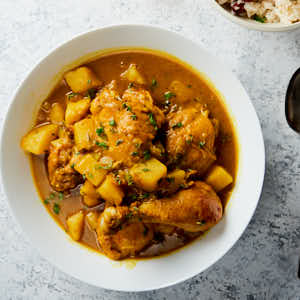 Jamaican curry chicken in a white bowl from above.