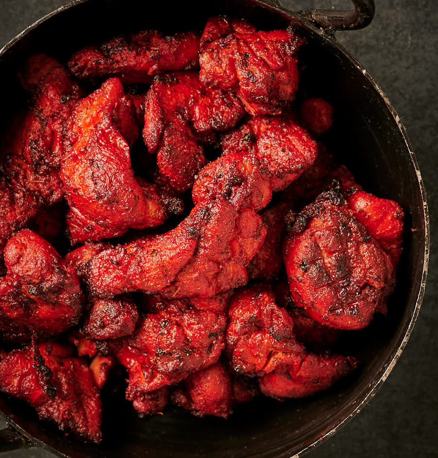 Grilled chicken tikka in a kadai from above.