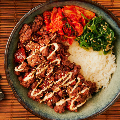 korean beef bowl with banchan and creamy Gochujang drizzle from above.