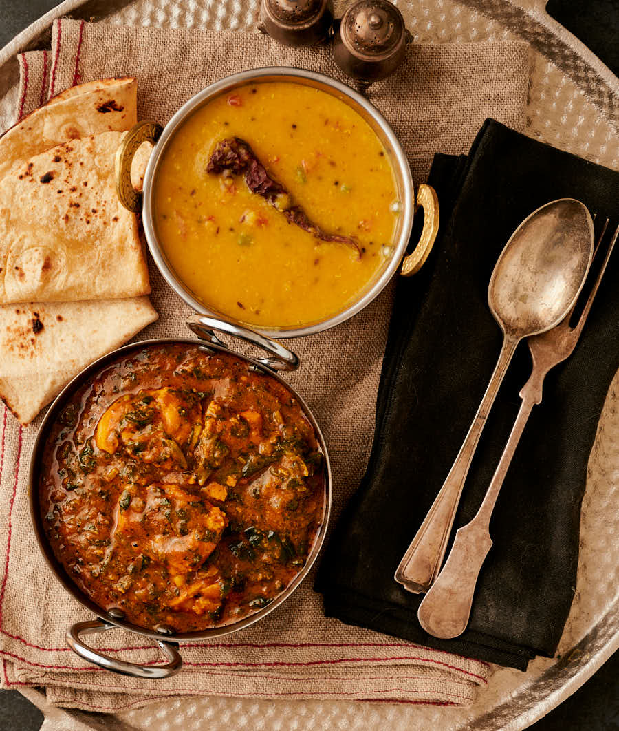 Table scene of palak chicken, tarka dal and chapati from above.