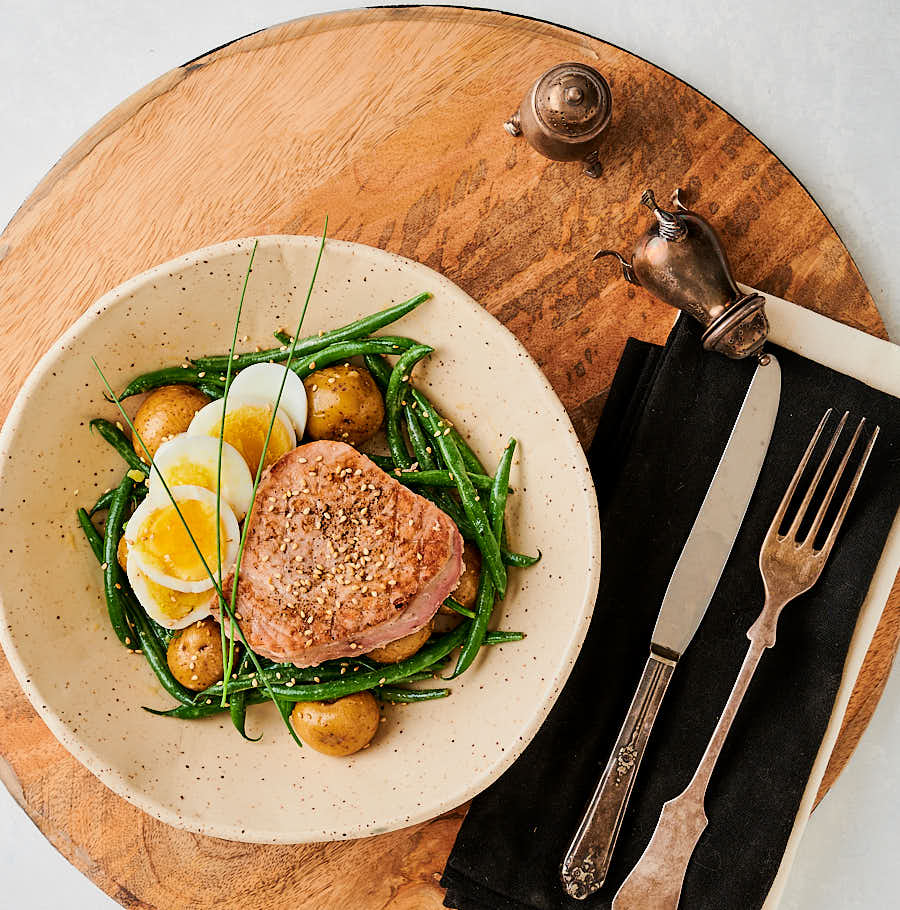 Japanese seared tuna on a bed of potatoes, green beans and sliced egg table scene.