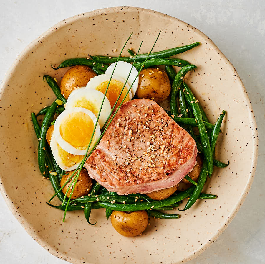 Bowl with seared Japanese tuna on a bed of green beans, potatoes and sliced egg