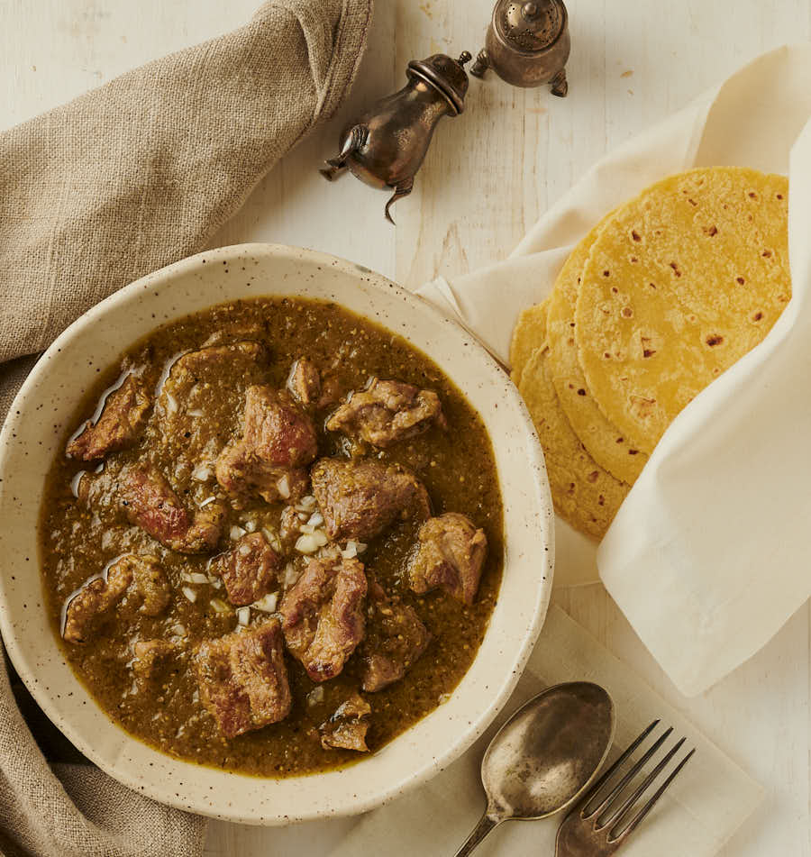 Table scene - bowl of chili verde, toritillas, cutlery and salt and pepper shakers