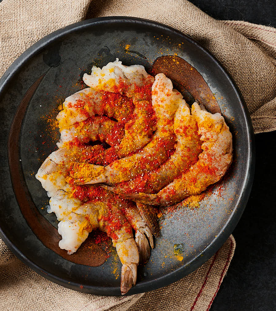 Seasoned raw shrimp in a bowl.