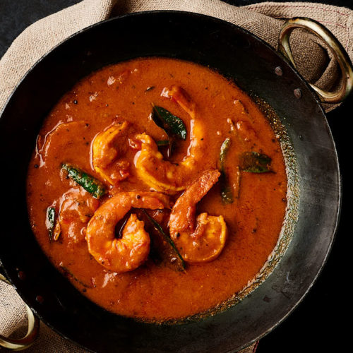 Prawn curry in a black kadai pan from above.
