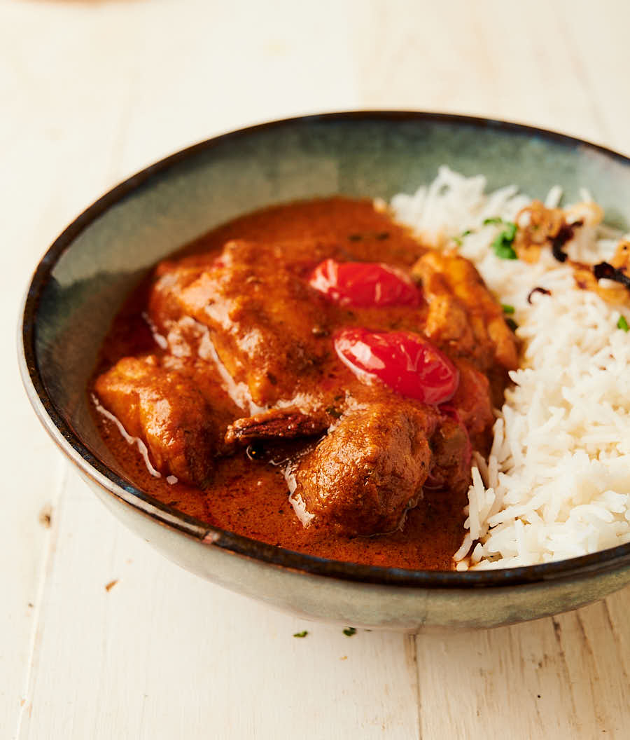 bowl of chicken rogan josh served with rice from the front.
