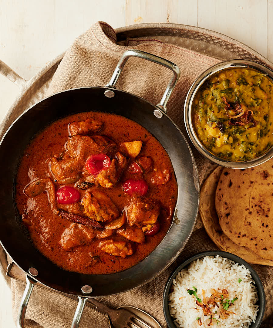 Chicken rogan josh table scene with dal, rice and chapatis.