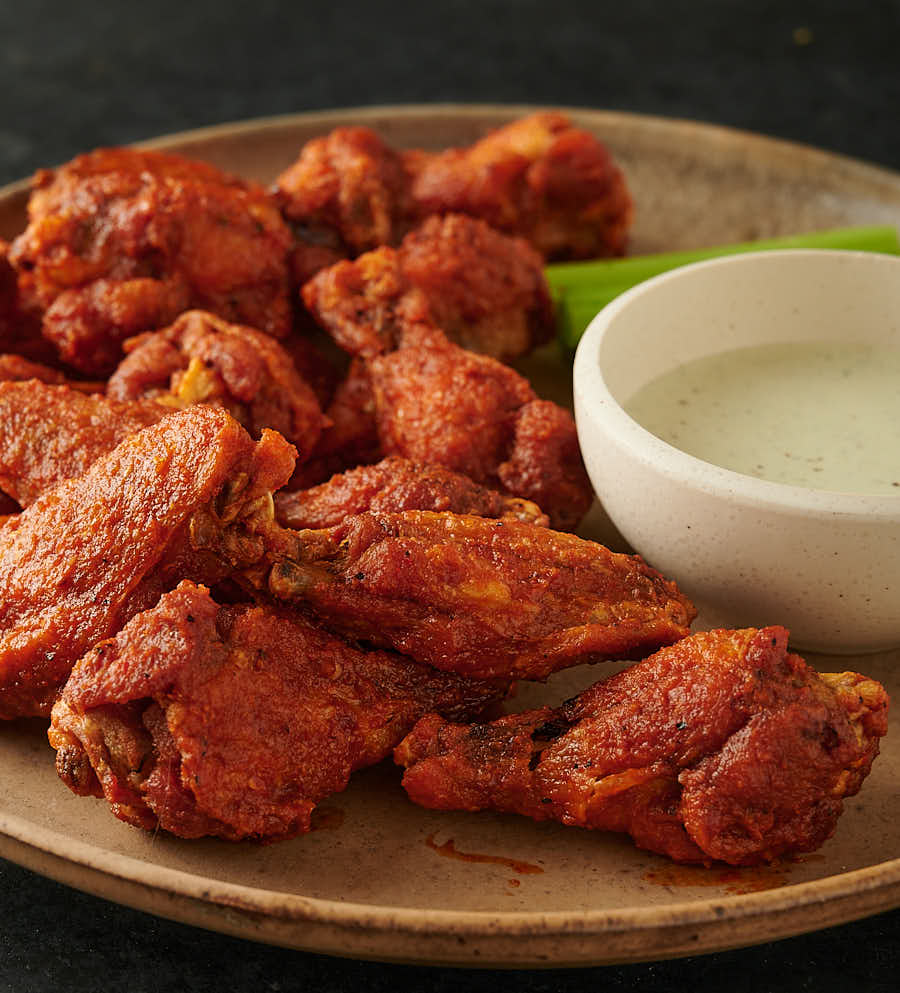 A mess of vindaloo chicken wings and dipping sauce from the front.