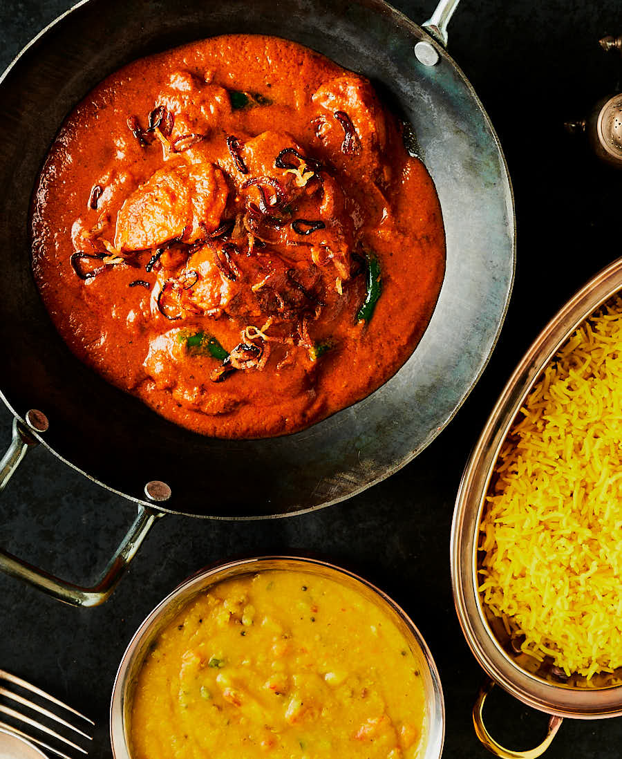 chicken changezi in a kadai with dal and rice from above.