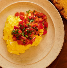 Closeup of ekoori tomato mixture on scrambled eggs from above.
