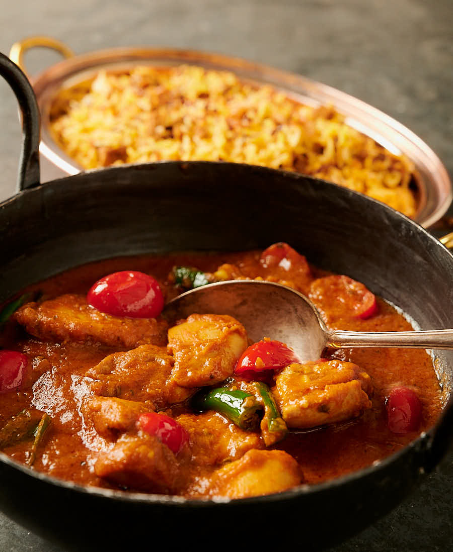 Bottle masala chicken curry with spoon.