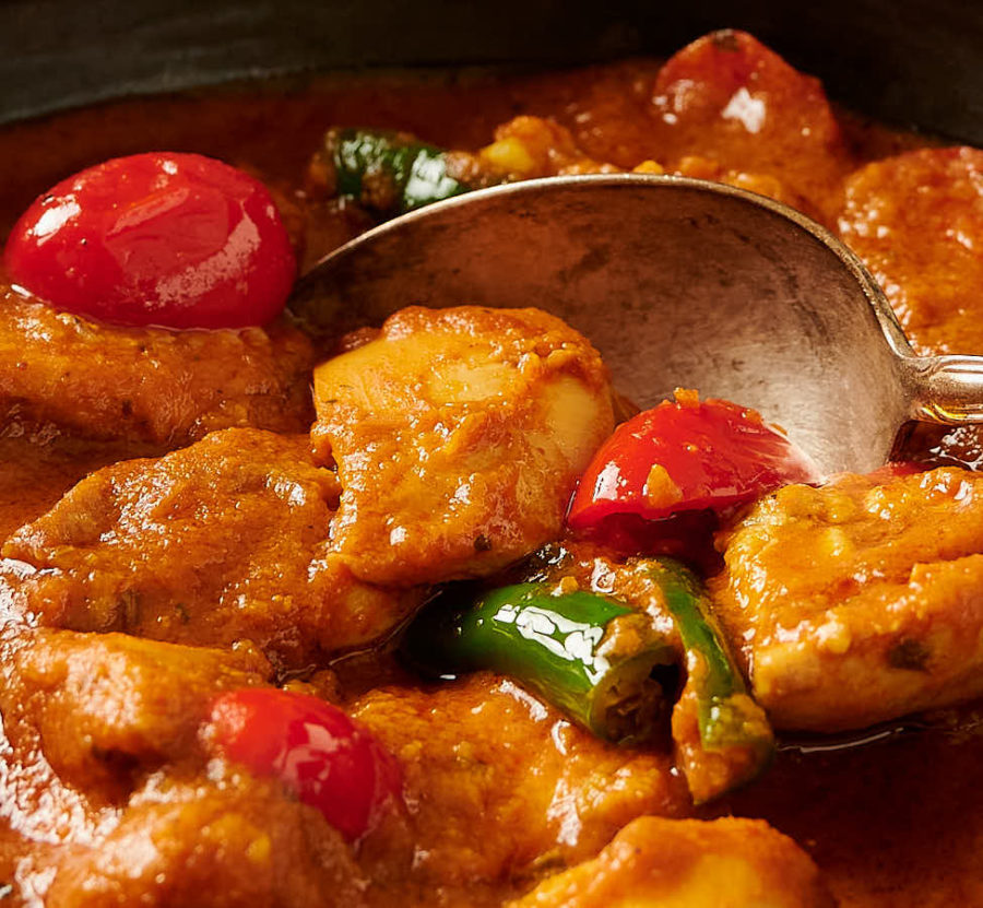 Close-up of chicken curry, chilies and tomato