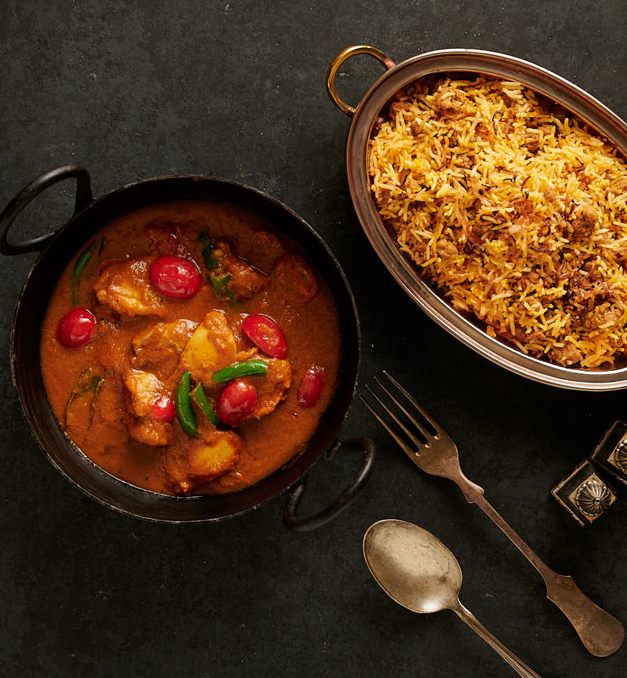 Table scene of bottle masala chicken curry and rice from above.