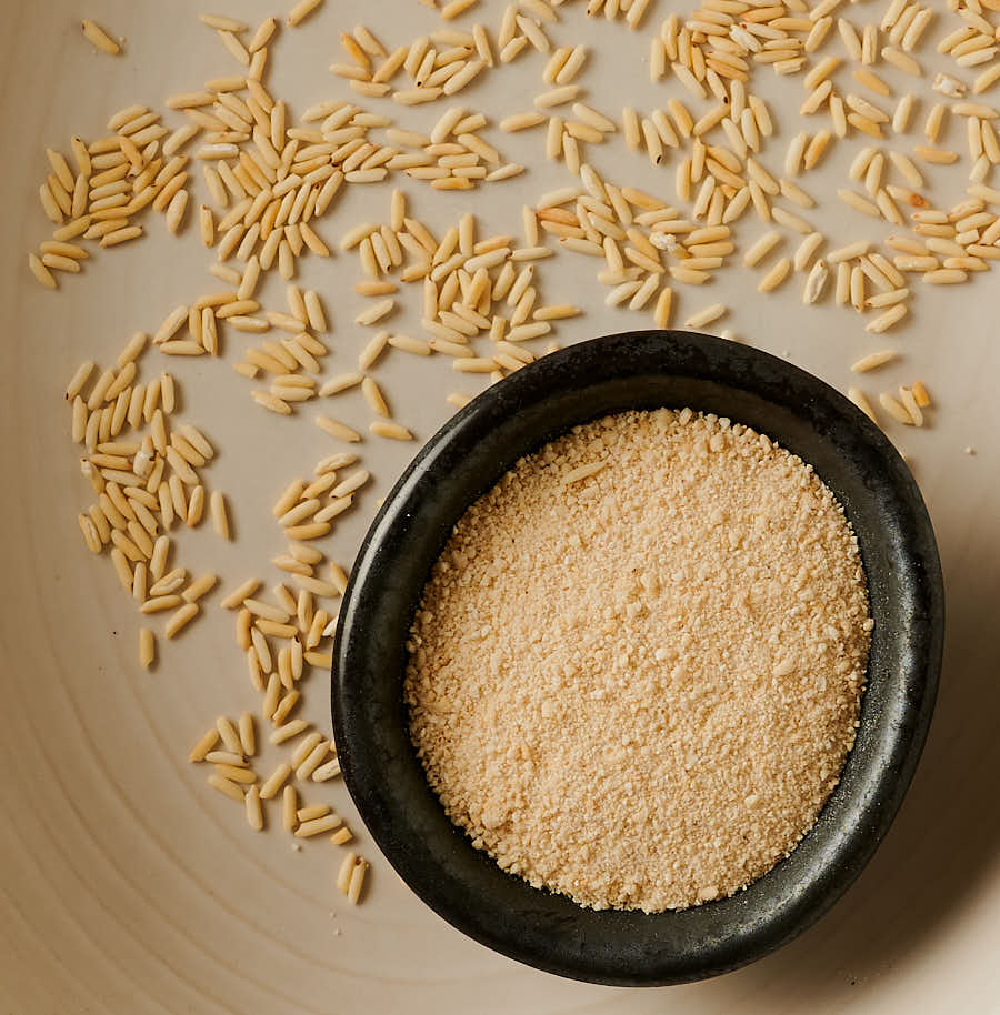 Toasted rice powder in a small bowl with toasted rice scattered around it.