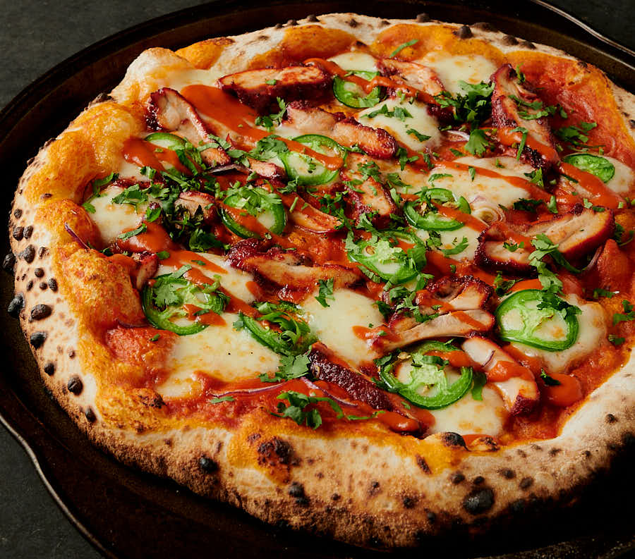 butter chicken pizza with jalapeños, drizzle and cilantro garnish from the front