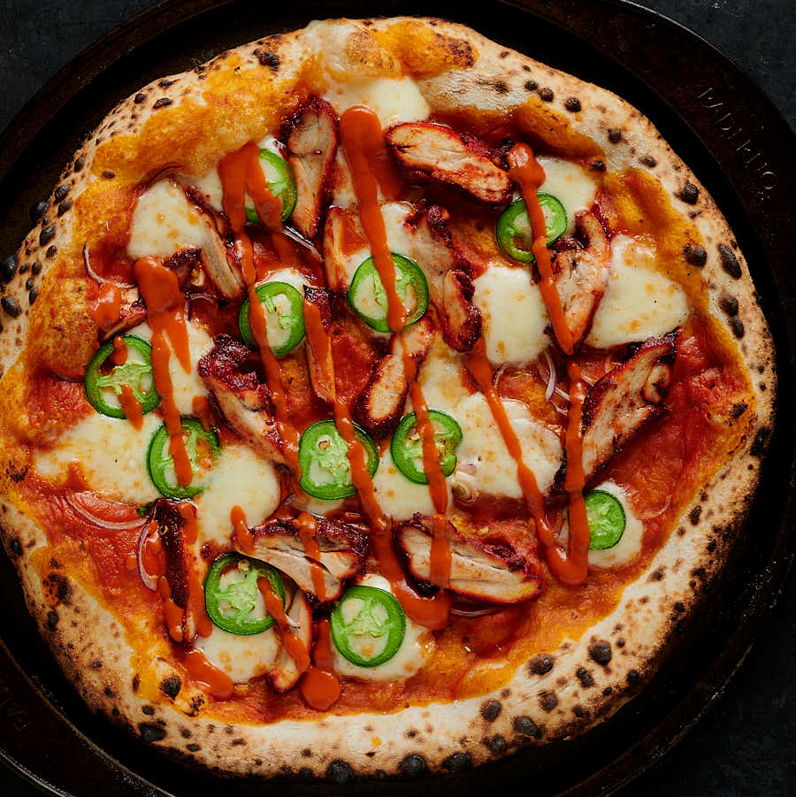 butter chicken pizza with butter chicken sauce drizzle from above