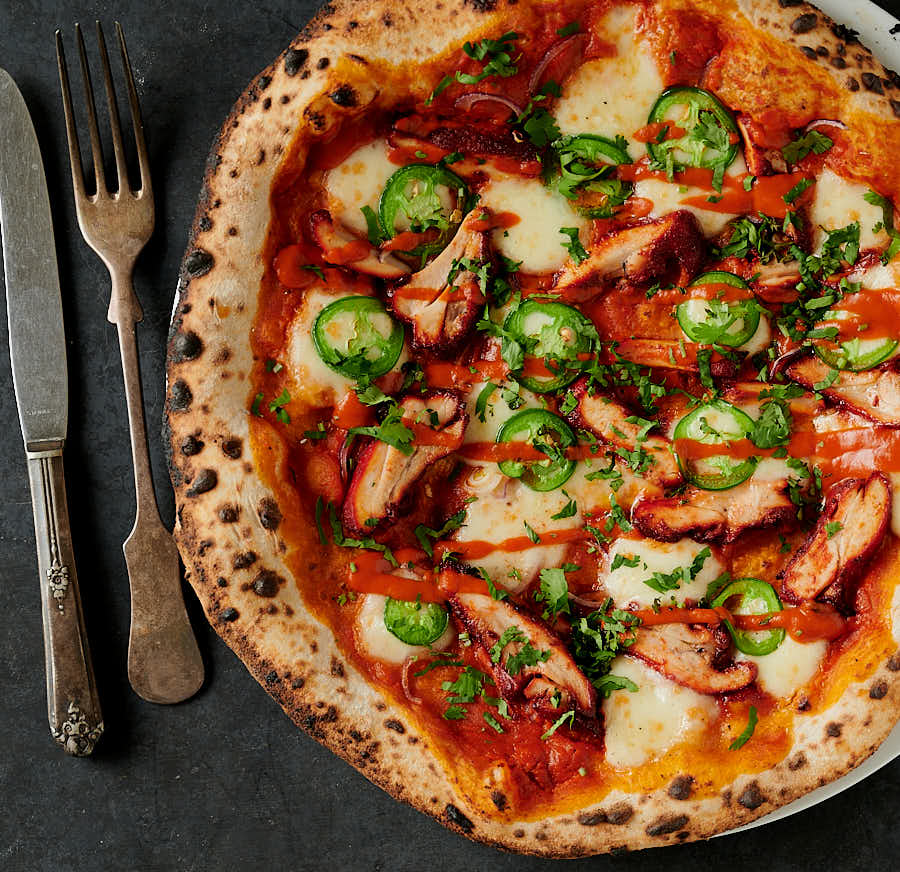 butter chicken pizza with knife and fork from above