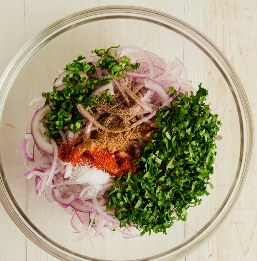 Indian onion salad ingredients in a clear bowl from above