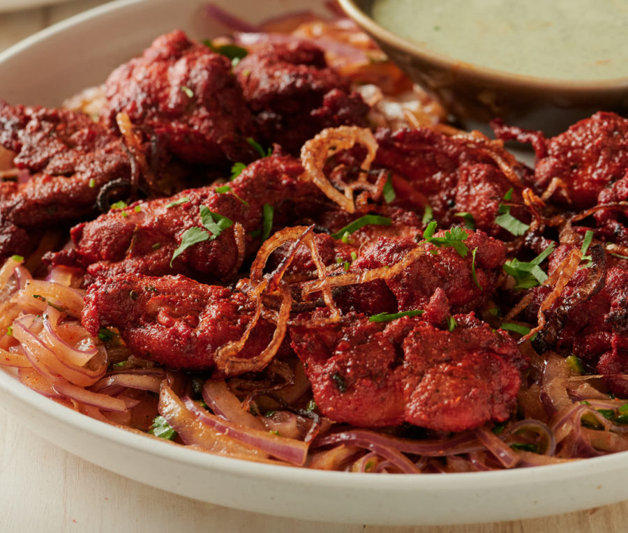 Tandoori chicken and dip on a bed of onion salad from above